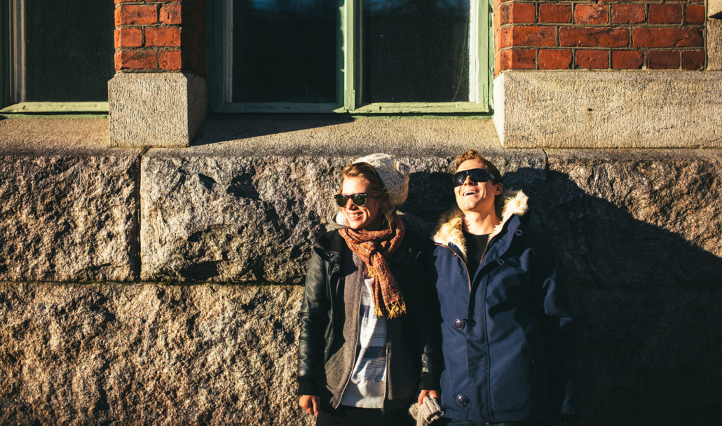 Two people with sunglasses leaning against a building wall