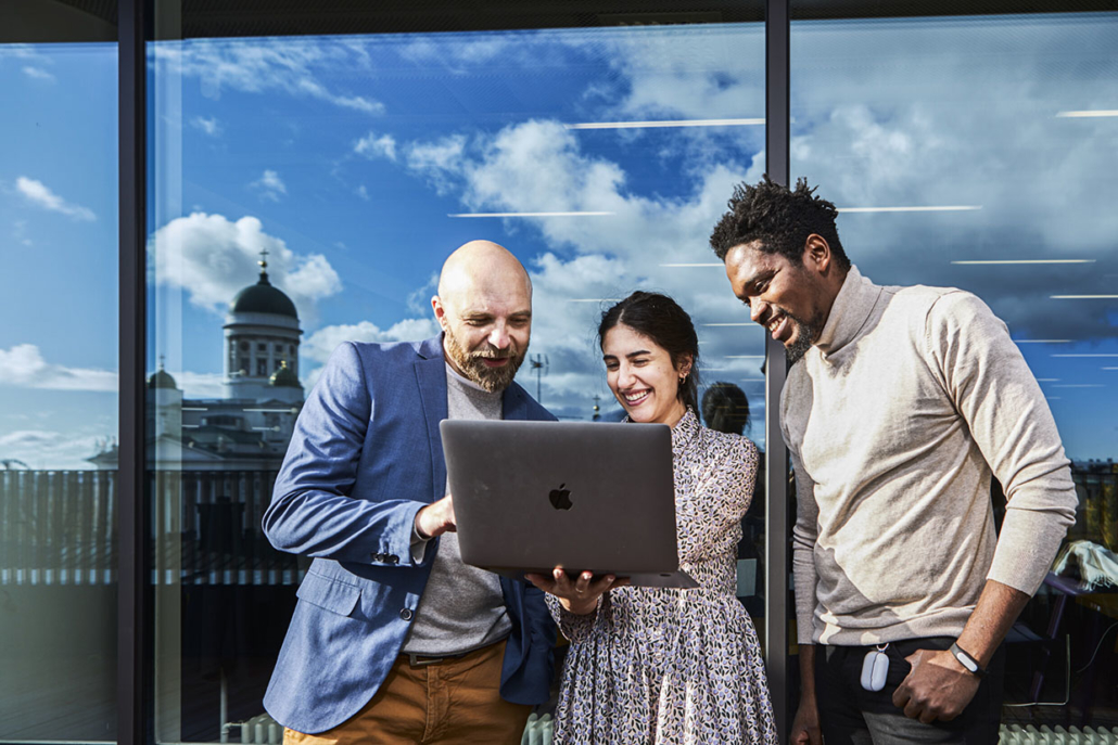 Two men and a woman looking at something on a laptop